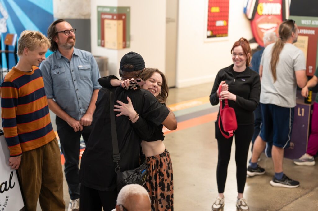 Guests greet each other with a hug in the atrium while friends look on.