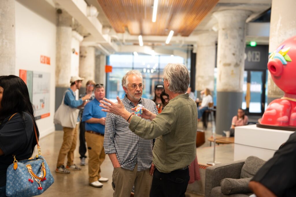 Two men talk and gesture animatedly in the open atrium.