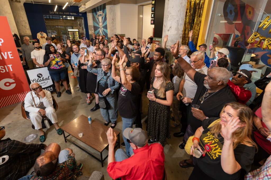 The crowd cheers with raised hands during the birthday program.